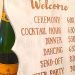 bottle of champagne next to wedding schedule sign